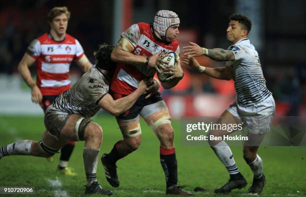 Ben Morgan of Gloucester is tackled by James Ratti and Jay Baker of Ospreys during the Anglo-Welsh Cup match between Gloucester Rugby and Ospreys at...