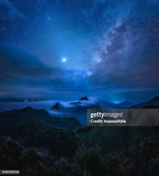 milky way above the mountainous landscape with misty at night - dark evening sky stock-fotos und bilder