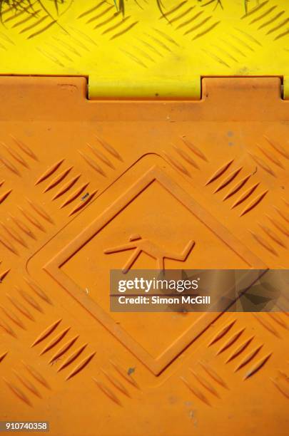 close-up of a trip hazard warning symbol on a plastic cover over electrical cables on a lawn - trip hazard stock pictures, royalty-free photos & images