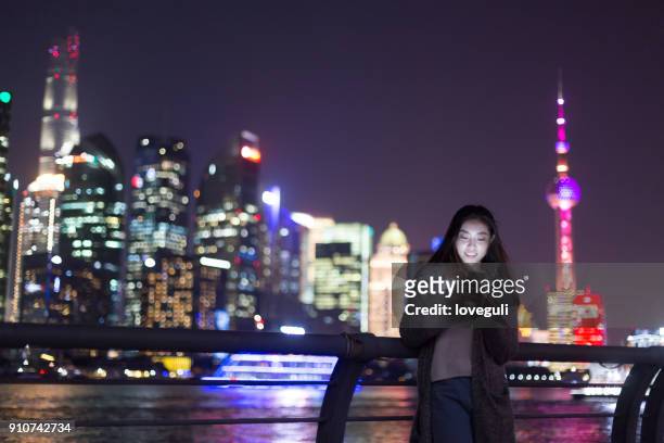 young asian woman plays with mobile phone in modern city - people shanghai stock pictures, royalty-free photos & images