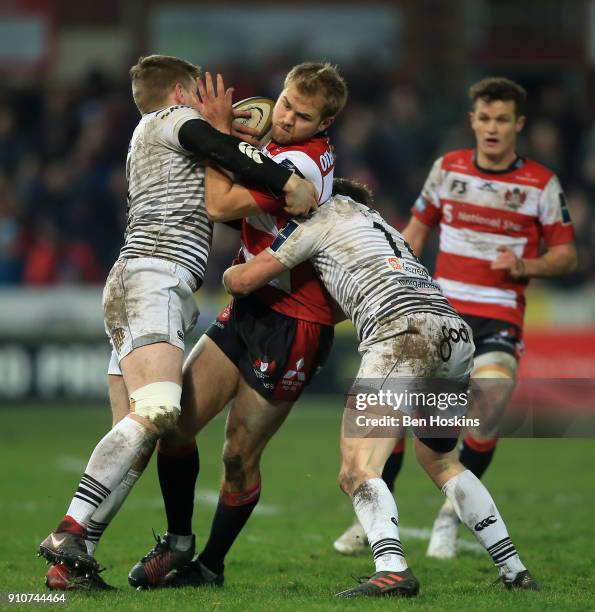 Tom Hudson of Gloucester is tackled by Dafydd Howells and Luke Price of Ospreys during the Anglo-Welsh Cup match between Gloucester Rugby and Ospreys...