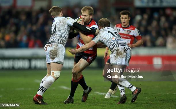 Tom Hudson of Gloucester is tackled by Dafydd Howells and Luke Price of Ospreys during the Anglo-Welsh Cup match between Gloucester Rugby and Ospreys...