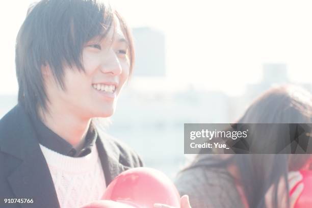 jonge vrouw en man knuffelen rood hart ballon op zonnige winterdag - young couple red sunny stockfoto's en -beelden