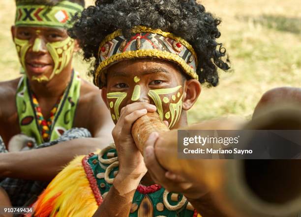 a tribesman playing didgeridoo at festival - dinagyang festival - fotografias e filmes do acervo