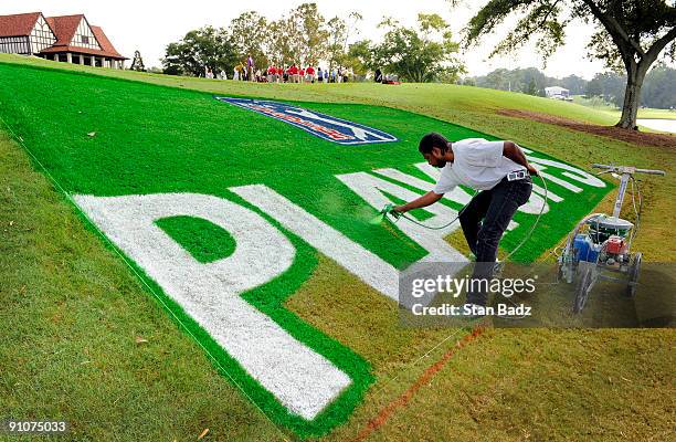 Charles English with Field Graphic Designs spray paints a PLAYOFFS logo on the clubhouse lawn during practice for THE TOUR Championship presented by...