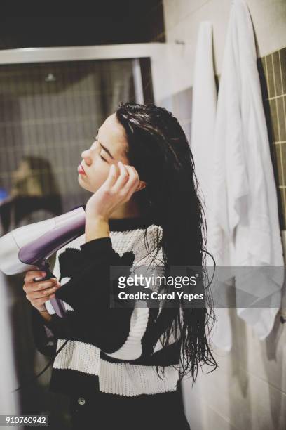 beautiful young woman looking at the mirror drying hair - hair dryer stock photos et images de collection