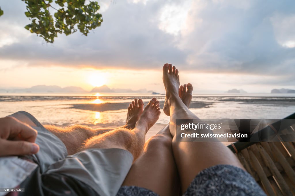 Personal perspective of couple relaxing on hammock, feet view
