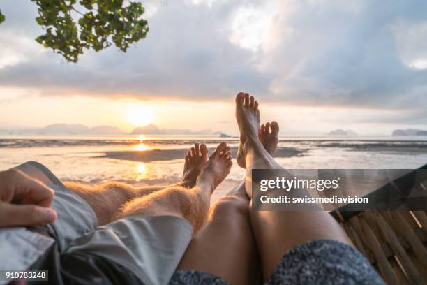 personal perspective of couple relaxing on hammock, feet view - barefoot couples stock pictures, royalty-free photos & images