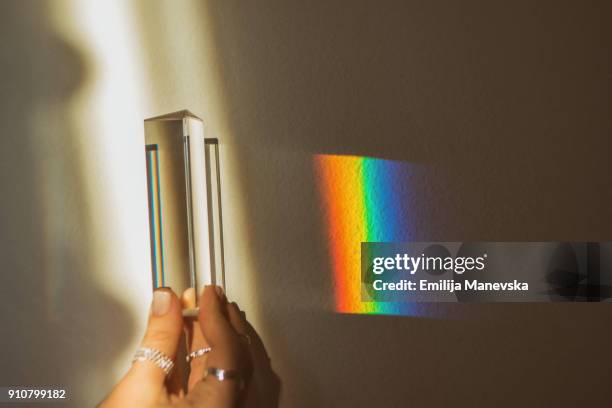 human hand holding optical prism while making rainbow reflection - プリズム　レンズ ストックフォトと画像