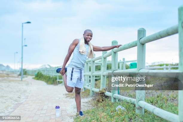 a young black man stretching. - black male bodybuilders 個照片及圖片檔