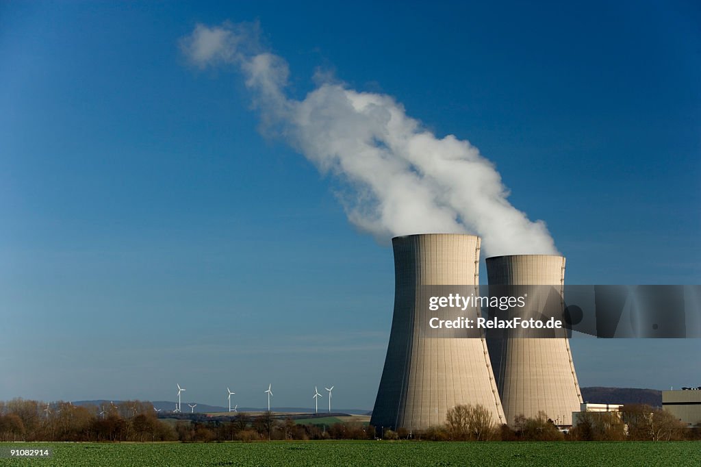 Two Steaming cooling towers and wind turbine farm