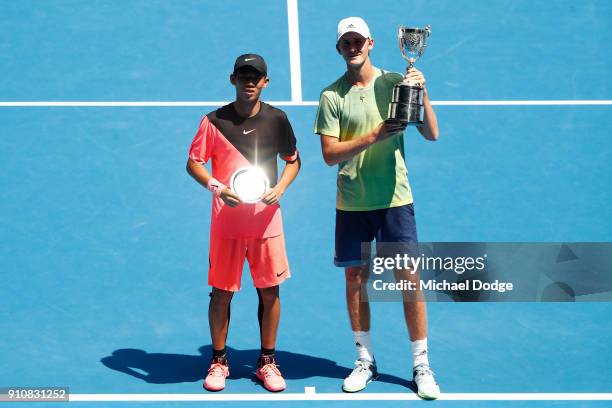 Chun Hsin Tseng of Chinese Taipei poses with the runners-up trophy and Sebastian Korda of the United States poses with the championship trophy after...