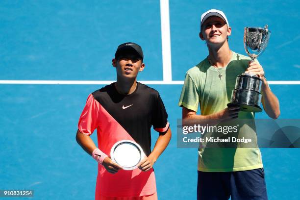 Chun Hsin Tseng of Chinese Taipei poses with the runners-up trophy and Sebastian Korda of the United States poses with the championship trophy after...