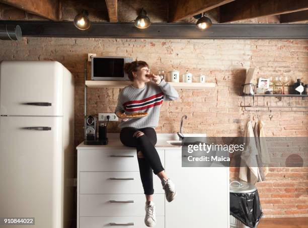 beautiful girl eating pizza in a modern kitchen - young cook imagens e fotografias de stock