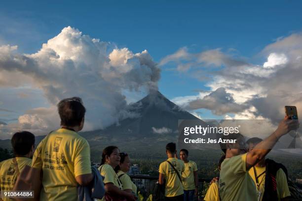 Visitors and residents flock to a viewing area to see Mayon volcano as it erupts on January 26 in Albay, Philippines. Over 70,000 villagers have been...
