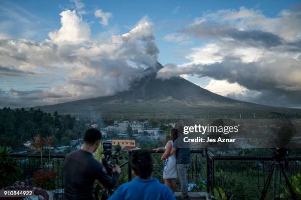 Video crew films a couple overlooking Mayon volcano as it spews ash and lava on January 26 in Albay, Philippines. Over 70,000 villagers have been...