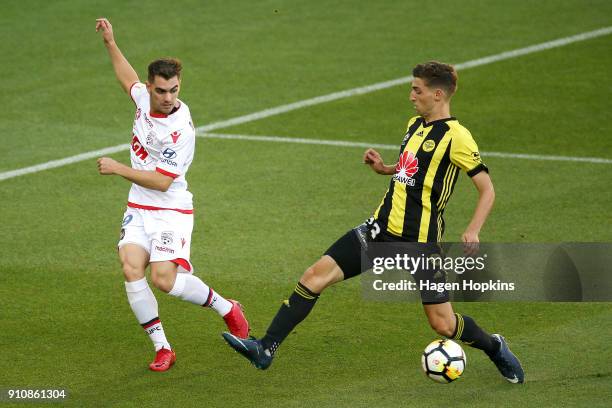 Ben Garuccio of Adelaide United passes under pressure from Matthew Ridenton of the Phoenix during the round 18 A-League match between the Wellington...