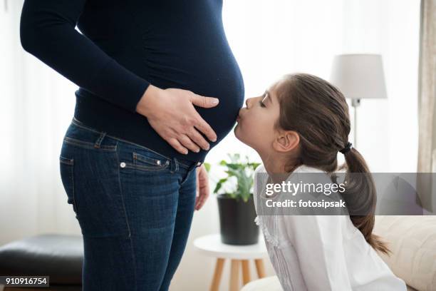 little girl kissing her sister in pregnant mother's belly - belly kissing stock pictures, royalty-free photos & images