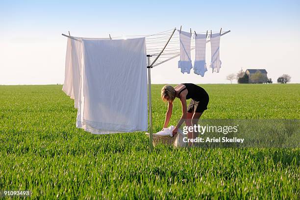 young woman doing laundry in field - hausfrau stock-fotos und bilder