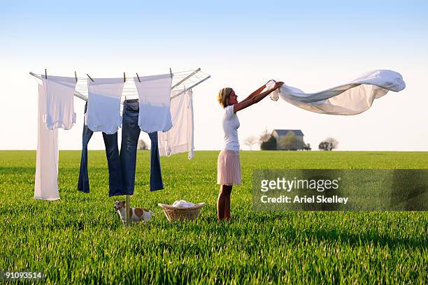 young woman doing laundry in field - wäscheleine stock-fotos und bilder
