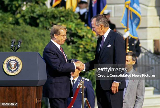 Czech President Vaclav Havel and US President George HW Bush shake hands on a reviewing stand on the White House's South Lawn during the former's...