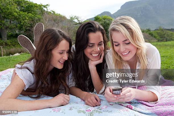 group of friends reading text messages on mobile - sólo chicas adolescentes fotografías e imágenes de stock