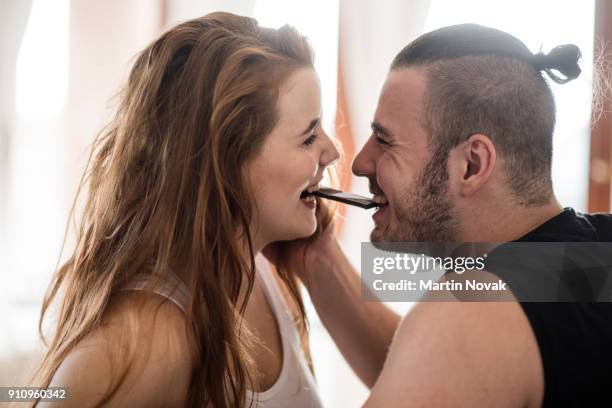 joyous young couple eating chocolate together - bites stock pictures, royalty-free photos & images