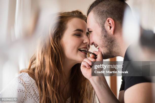 closeness of a couple while sharing chocolate - cute girlfriends stock pictures, royalty-free photos & images