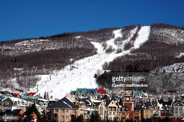 panoramic view of a ski hill with village below - mont tremblant stock pictures, royalty-free photos & images