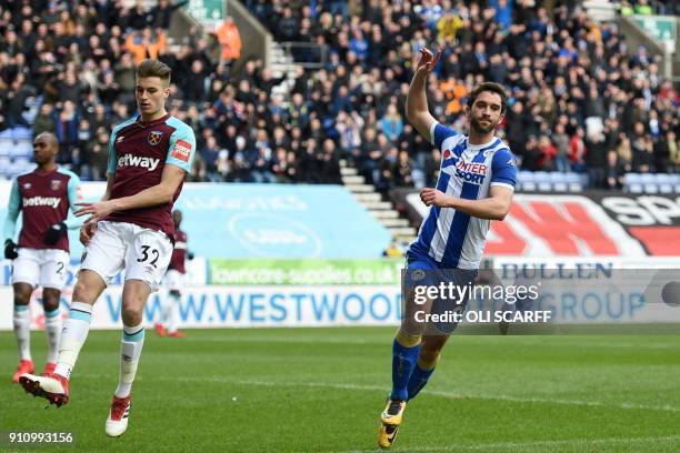 West Ham United's English defender Reece Burke reacts as Wigan Athletic's English-born Northern Irish striker Will Grigg celebrates scoring the...