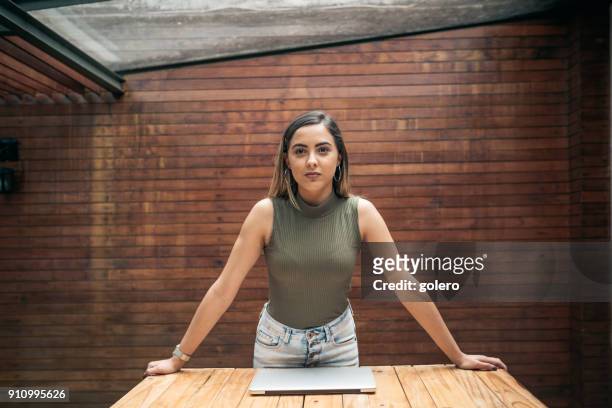 confident young brazilian businesswoman leaning on desk - founder stock pictures, royalty-free photos & images