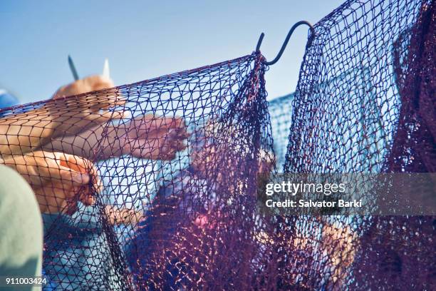 mending their nets - commercial fishing net stock pictures, royalty-free photos & images