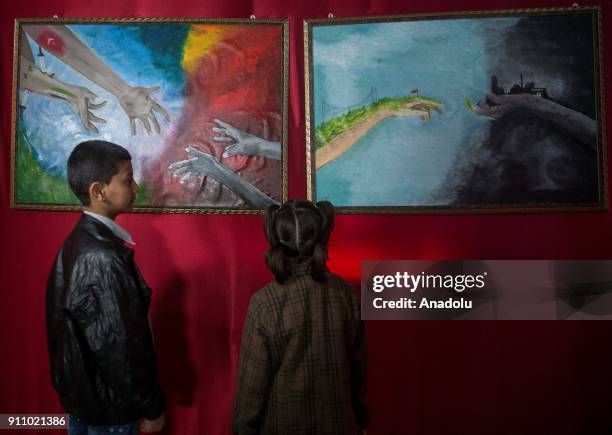 Kids inspect the paintings of Syrian painters Fatima Ahmed and Hikmet Ismael during an art exhibition which is on Syrian people's experience, natural...