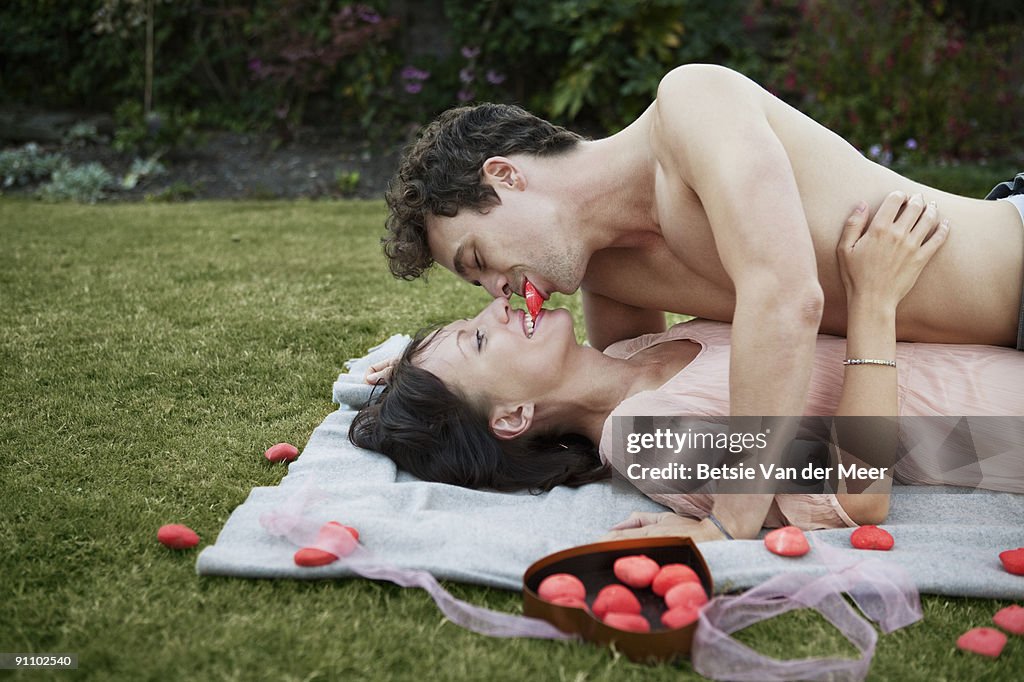 Couple laying in grass sharing sweets.