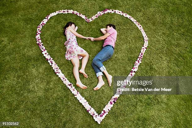 couple laying in heart-shaped rosepedals. - betsie van der meer stock pictures, royalty-free photos & images