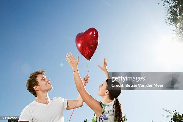 woman trying to catch men's heartshaped balloon  - betsie van der meer stock pictures, royalty-free photos & images