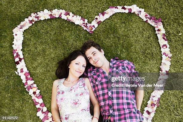 couple surrounded with heartshaped rosepedals. - betsie van der meer stock pictures, royalty-free photos & images