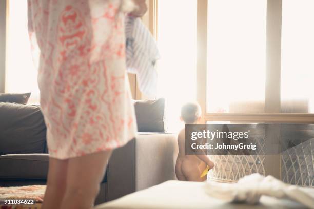 naked baby boy standing by window with mother in foreground - boys bare bum stock pictures, royalty-free photos & images