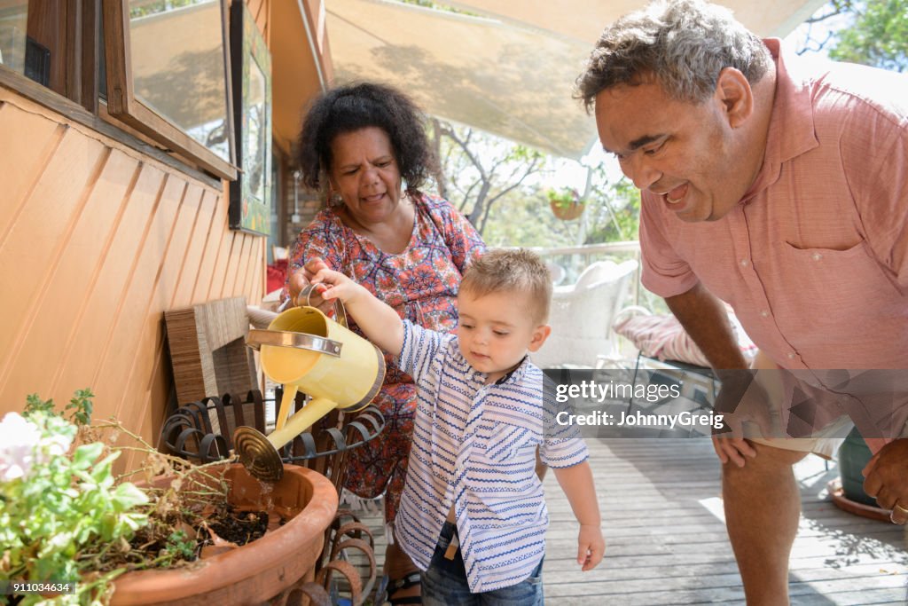 Baby boy watering plants with grandparents