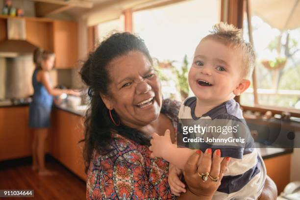 赤ちゃん孫を保持しているアボリジニの祖母の肖像画 - オーストラリア文化 ストックフォトと画像