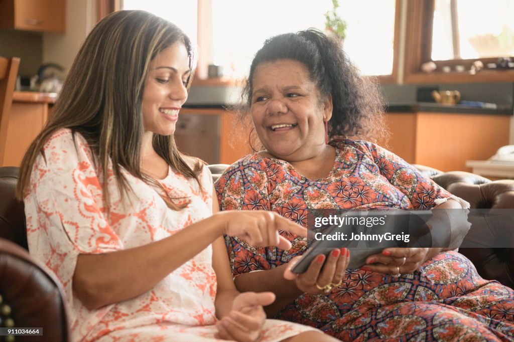 Two women using digital tablet smiling and laughing