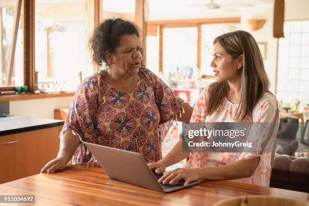 aboriginal mother talking to daughter working at home on laptop - minority groups stock pictures, royalty-free photos & images