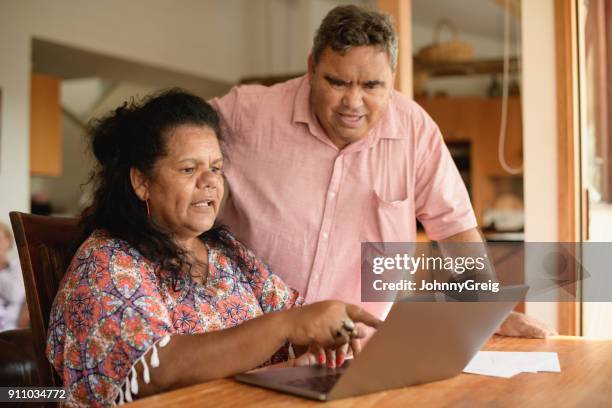 couple senior avec ordinateur portable femme pointant - australian culture stock photos et images de collection