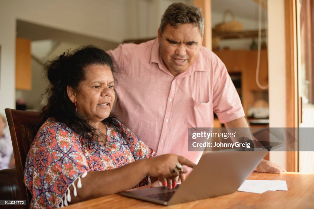 Mature couple using laptop with woman pointing