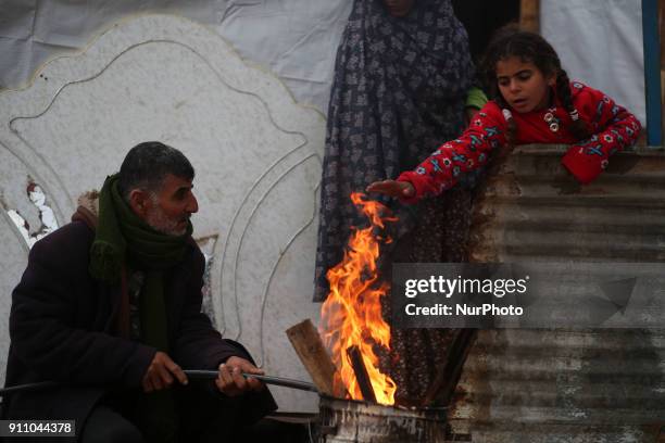 Palestinian family warm themselves by a fire outside their house North of Gaza City during a storm in Gaza Strip on January 27, 2018.