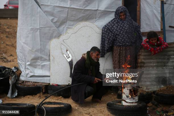 Palestinian family warm themselves by a fire outside their house North of Gaza City during a storm in Gaza Strip on January 27, 2018.