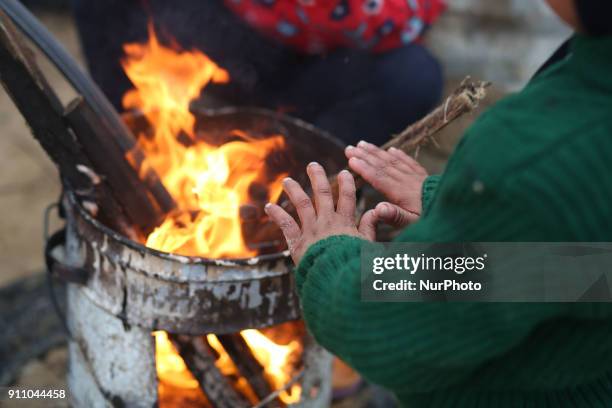 Palestinian family warm themselves by a fire outside their house North of Gaza City during a storm in Gaza Strip on January 27, 2018.