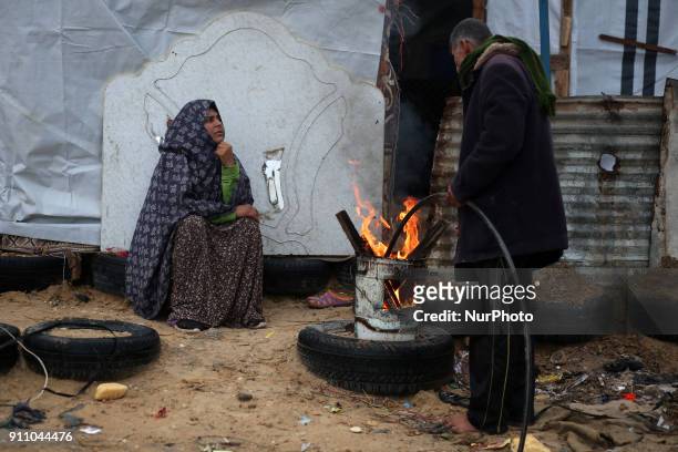 Palestinian family warm themselves by a fire outside their house North of Gaza City during a storm in Gaza Strip on January 27, 2018.