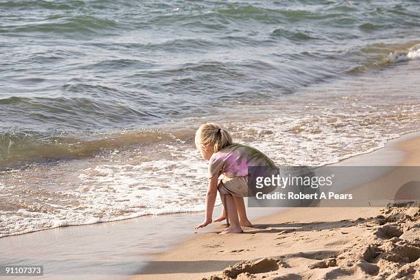 young girl playing on the beach - kenni stockfoto's en -beelden