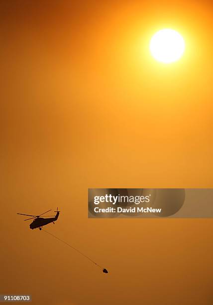 Firefighting helicopter flies at sunset on the eastern flank of the 16,000-plus-acre Guiberson fire, burning out of control for a second day as Red...